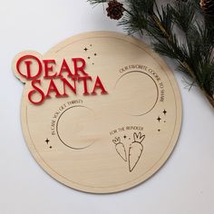 a wooden ornament with the words dear santa written on it and a pine branch