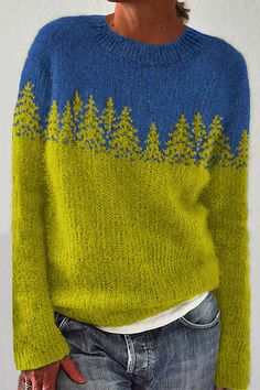 a woman wearing a green and blue sweater with pine trees on it's back