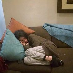 a woman laying on top of a couch covered in pillows