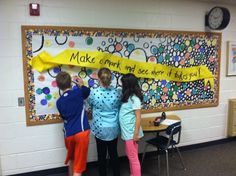 three children standing in front of a bulletin board