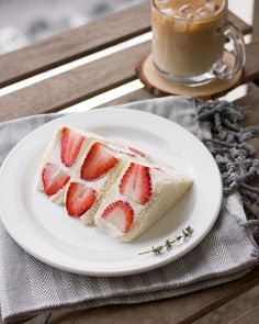 a piece of cake sitting on top of a white plate next to a cup of coffee