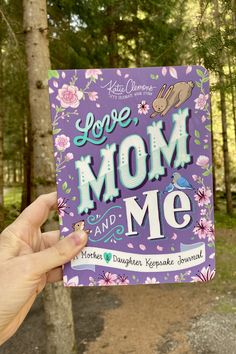 a hand holding up a purple book that says, you're mom and me