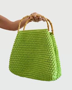 a woman's hand holding a green purse