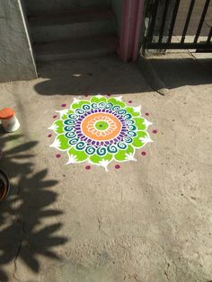 a colorful flower design painted on the ground next to a bike and steps with potted plants