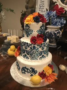 a three tiered cake decorated with flowers and lemons sits on a table in front of other desserts