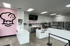 the interior of a restaurant with pink walls and black lettering on the wall that says order