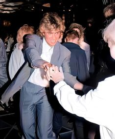 two men in suits are dancing at a party