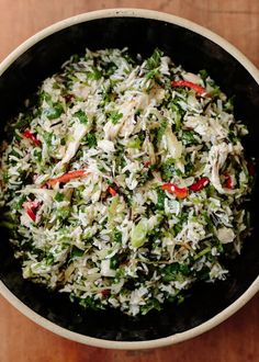 a bowl filled with rice and vegetables on top of a wooden table