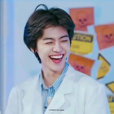 the young man is smiling and wearing a lab coat