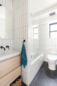 a white bathroom with black and white floor tiles on the walls, tub, toilet and sink