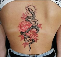 a woman's back with a snake and flowers tattoo on her left side ribcage