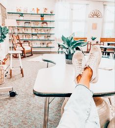 a person's feet resting on a table in a room with chairs and tables