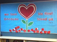 there is a banner with hearts and a flower in the center that says, we love because he first loved us