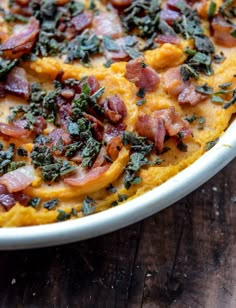 a casserole dish with bacon, spinach and cheese in it on a wooden table