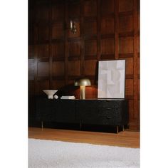 a black dresser sitting on top of a hard wood floor next to a white rug