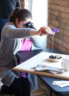 a woman sitting at a table with a cup and spoon in front of her face