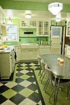 a kitchen with green walls and black and white checkered flooring on the floor