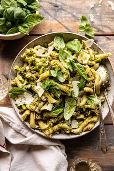 a bowl filled with pasta and spinach on top of a wooden table next to other dishes