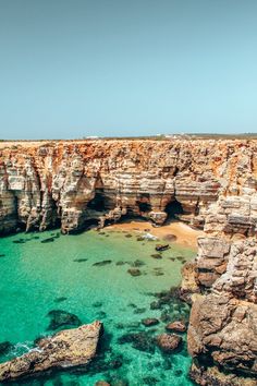 an aerial view of the ocean and rocky coastline with clear blue water, rocks and cliffs