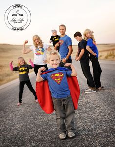 a group of people standing on the side of a road with a child dressed as superman