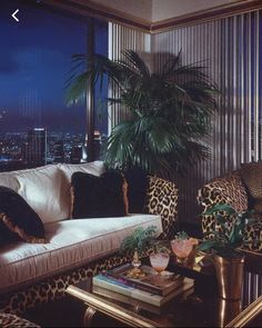 a living room filled with lots of furniture and a large window overlooking the city at night