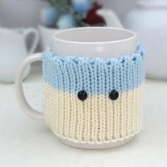 a knitted coffee cup with two black buttons on the inside and one blue button on the outside