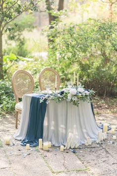 the table is set up with candles and flowers for an outdoor wedding reception in the woods