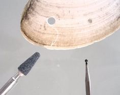 three different tools are laying on the table together, including a knife and an object with holes in it