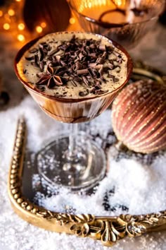 a dessert in a glass with chocolate toppings on the rim and an ornament next to it