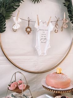 a baby's bodysuit hanging on a clothes line next to cakes and cupcakes