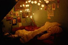 a bedroom with lights strung from the ceiling and pictures on the wall above it,