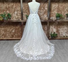 a white wedding dress with flowers on the skirt and back, is displayed in front of a