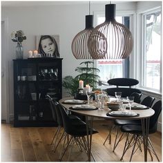 a dining room table set with place settings and candles in front of the window, next to a black bookcase