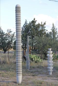 two tall white sculptures sitting in the middle of a field