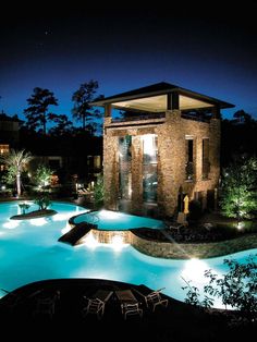 an outdoor swimming pool at night with lights