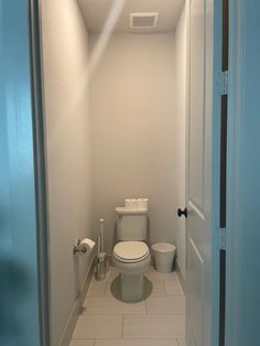 a white toilet sitting inside of a bathroom next to a door