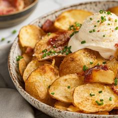 a bowl filled with potato wedges topped with sour cream