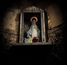 an image of the virgin mary on display in a window with flowers and candles around it