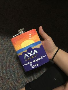 a person holding up a flask shaped like a hip flask with the words axa written on it