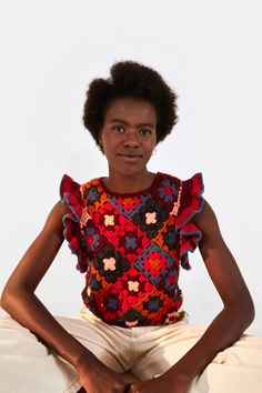 a woman sitting on top of a bed with her hands in her pockets and looking at the camera