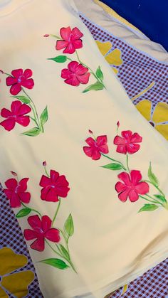 a white sheet with red flowers on it sitting on a blue and yellow checkered table cloth