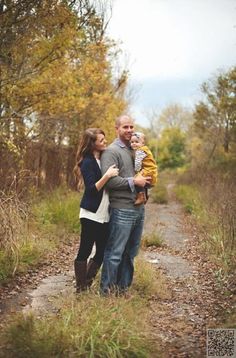 a man, woman and child standing on a path in the woods