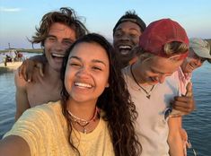 a group of young people standing next to each other near the water smiling at the camera