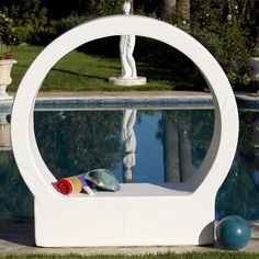 a white sculpture sitting in front of a swimming pool