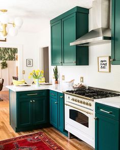 a kitchen with green cabinets and an area rug on the floor in front of the stove