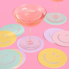 there are many different colored glasses with smiley faces on the plates next to each other