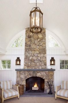 a living room with a stone fireplace and two chairs