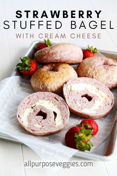 strawberry stuffed bagel with cream cheese is on a platter next to strawberries