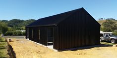 a black building sitting on top of a dirt field