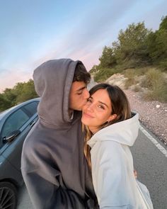 two people standing next to each other in front of a car